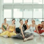 Gestire l’ansia prima di un’audizione Gruppo di giovani ballerine in tutù sorridenti sedute insieme in una sala luminosa