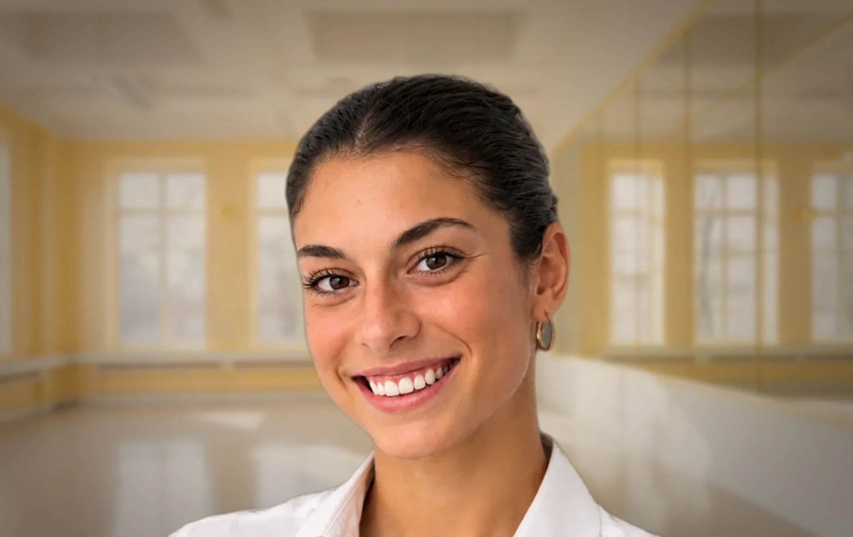 Primo piano sorridente di Carola Sicheri con sala di danza luminosa sullo sfondo